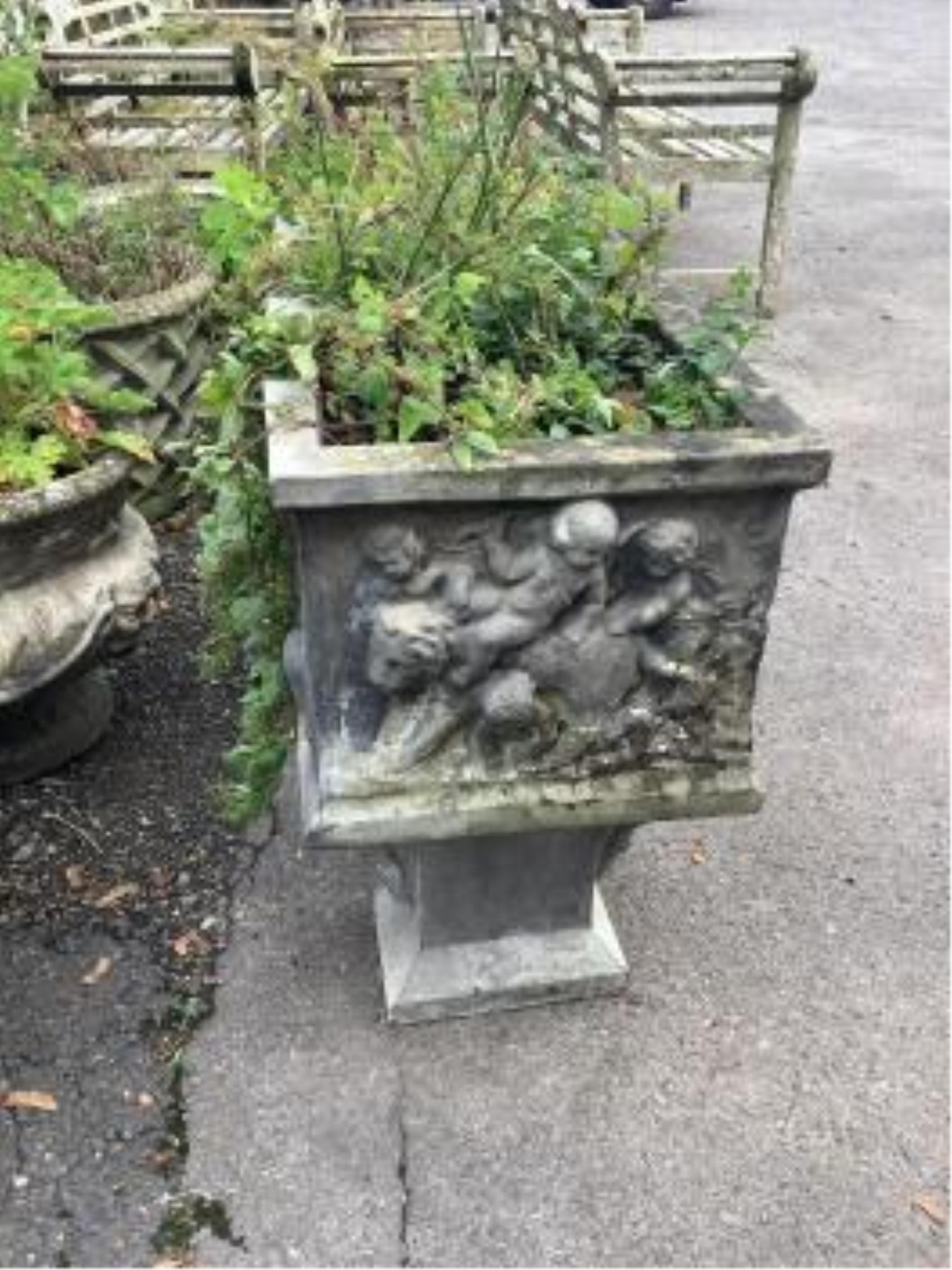 A reconstituted stone rectangular garden trough, moulded with putti, on Roman end plinths, width 89cm, depth 39cm, height 64cm. Condition - fair